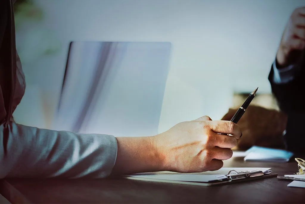 Mains d'une personne remplissant des documents administratifs pour l'accompagnement des familles.