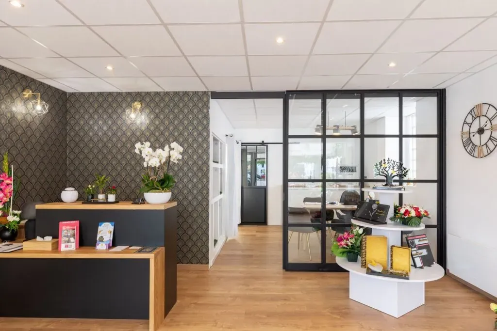 Comptoir d'accueil de l'agence funéraire avec orchidée et plaques souvenir.