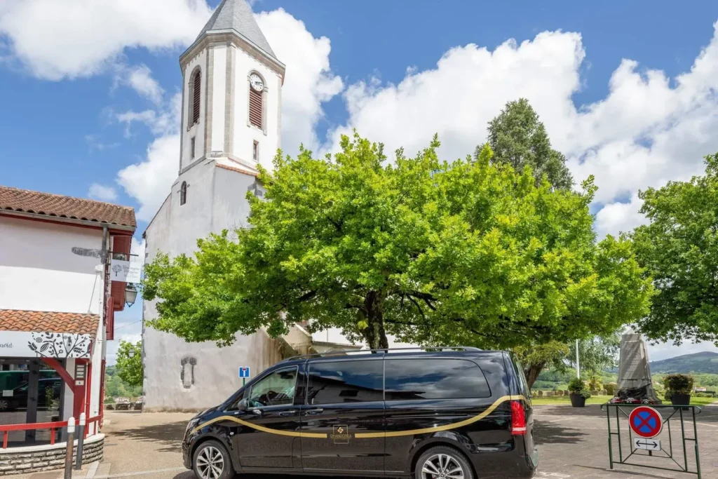 Véhicule funéraire noir Mercedes garé devant l'église d'un village du Pays basque.